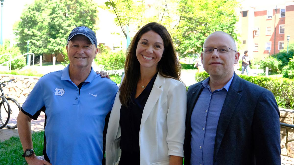 Jeff Greene, Erianne Weight and Anson Dorrance stand shoulder to shoulder.